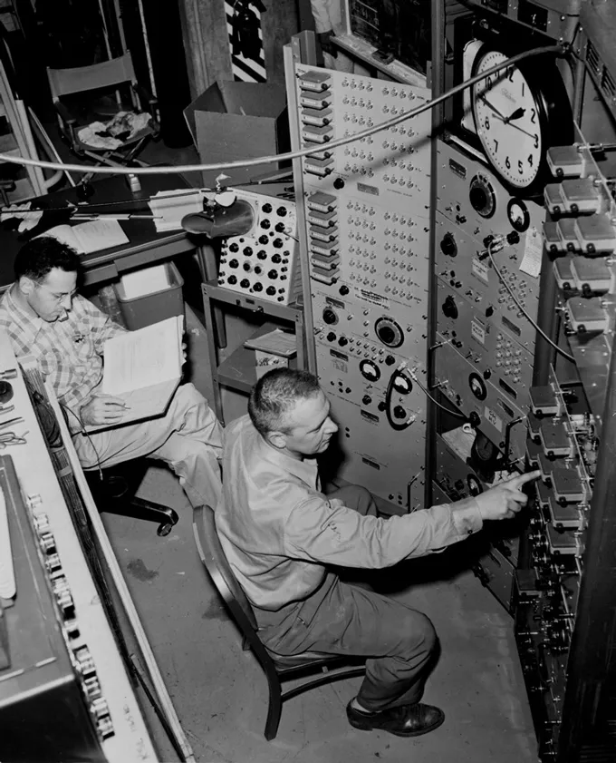 Two men monitor controls at a nuclear reactor.