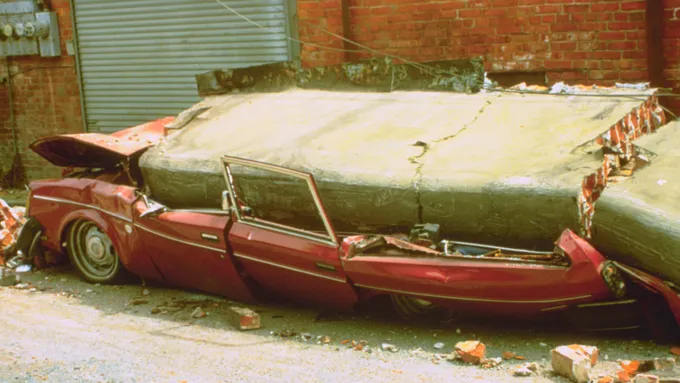 A 1992 photograph of a car crushed by falling bricks from a house, triggered by the magnitude 7.2 Cape Mendocino earthquake. A hidden tectonic plate boundary may have been the source.