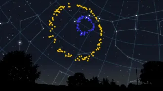 A big yellow ring encircles a smaller blue ring against a backdrop of stars and constellations