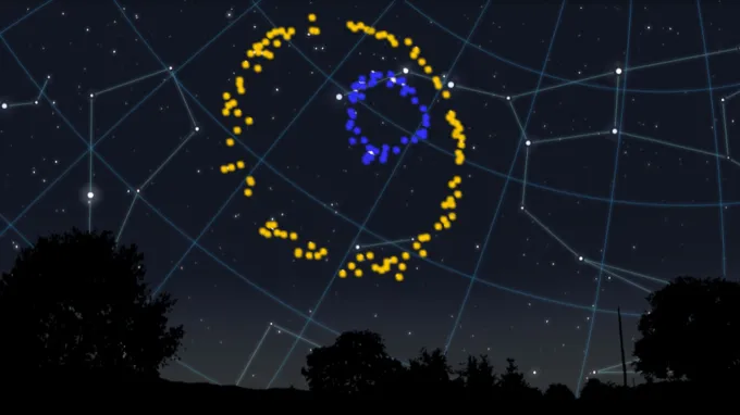 A big yellow ring encircles a smaller blue ring against a backdrop of stars and constellations