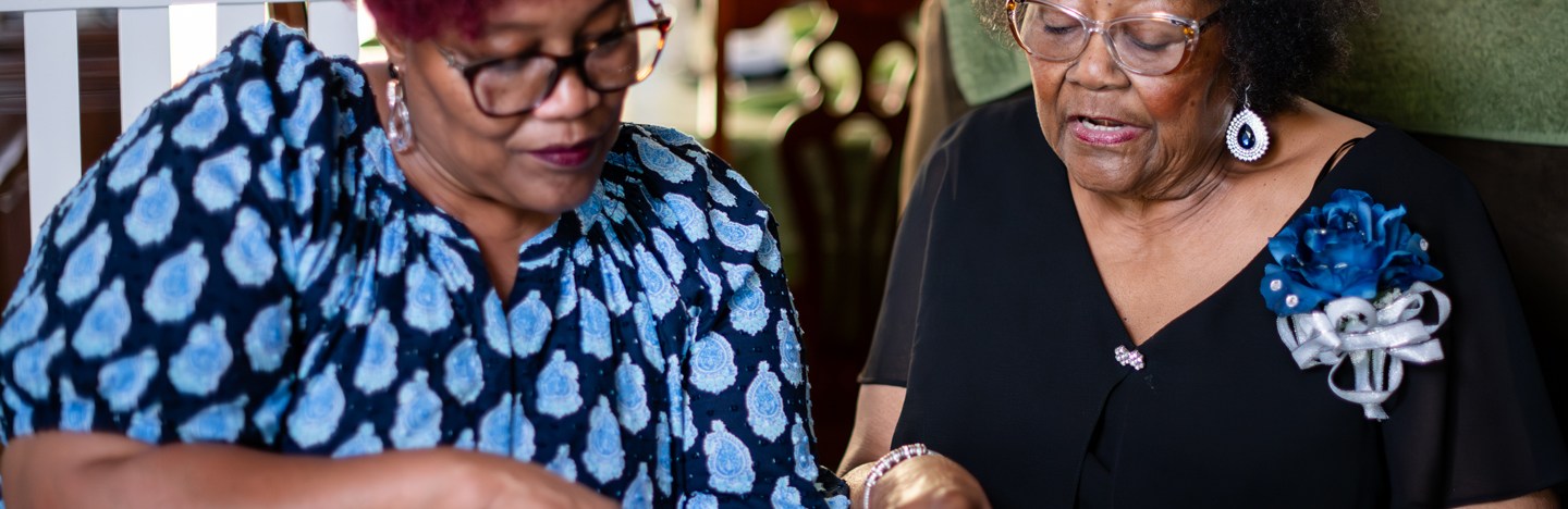 Two women read a book together.