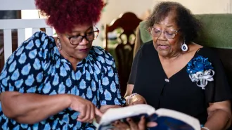 Two women read a book together.