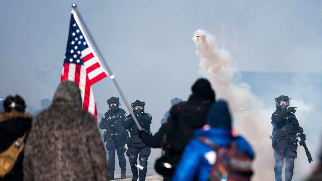A tear gas canister flies toward a crowd of people.