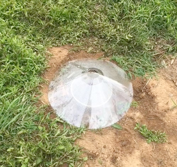 A cone of plastic sits on dirt.