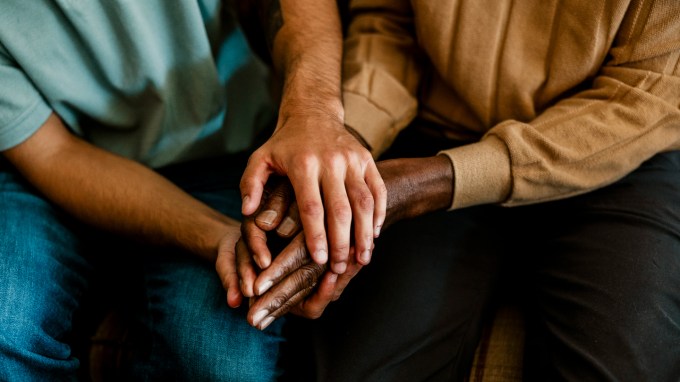 This image shows young hands holding older hands in a caring way, to imply caregiving.