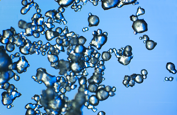 A closeup image of artificial snow. The snow appears grayish white against a blue background.