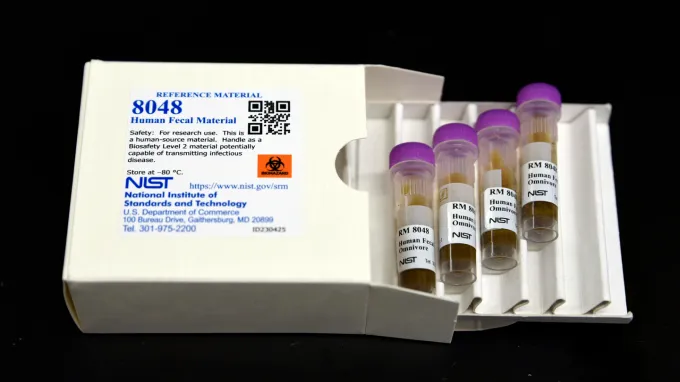 A box labeled Human Fecal Material is open with four vials of samples visible.
