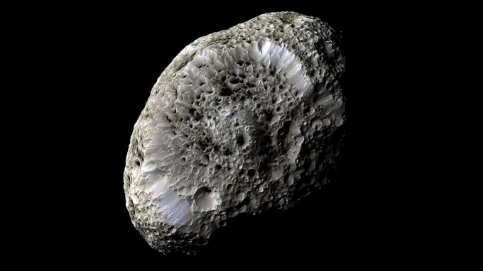 An egg-shaped moon covered in irregular craters on a black background