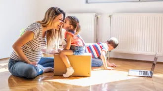 A woman nuzzles her nose against a child that is sitting on a small box. With fertility rates plummeting worldwide, pronatalists are urging people to have more babies.