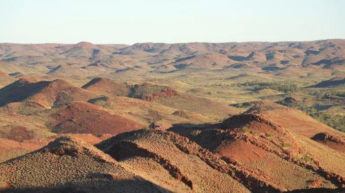A series of rusty-colored hills stretch into the distance. Rocks here hold the earliest known evidence of plate tectonics, a new study says.
