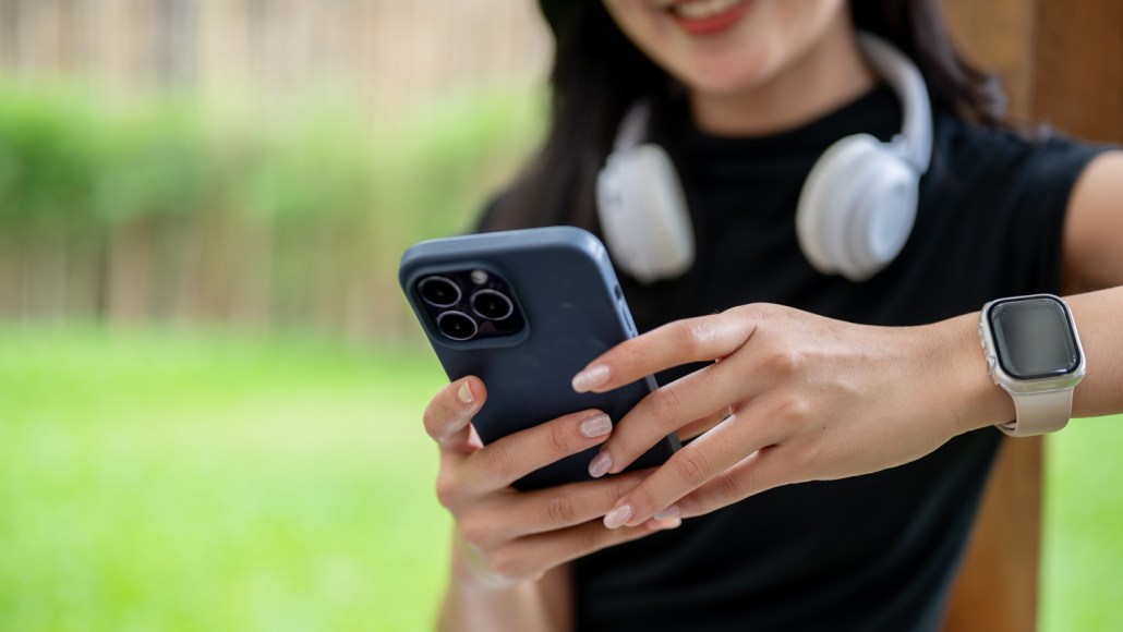 A woman with long nails uses her phone's touchscreen