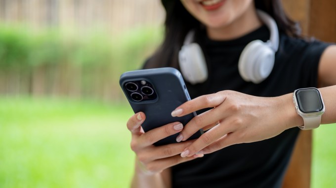 A woman with long nails uses her phone's touchscreen