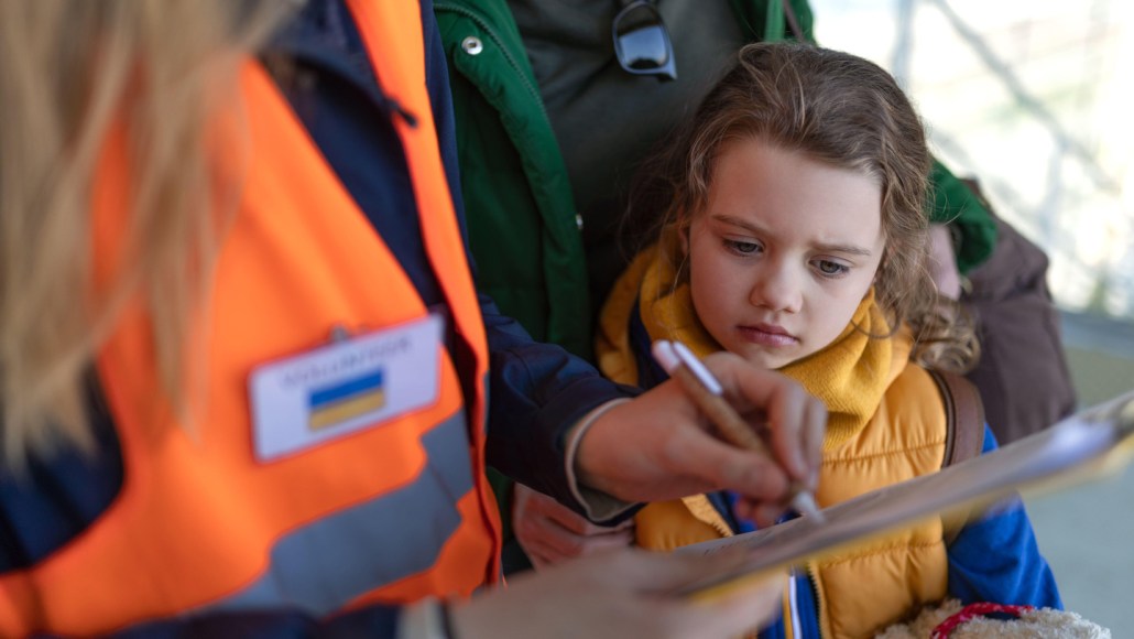 A young girl looks at a document that a woman is showing her.