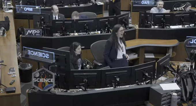 Two people, one sitting, one standing, behind a bank of computer screens labelled SCIENCE show visible astonishment, happiness.