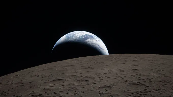 A crescent of Earth hangs over the horizon of the moon, as the planet sets. The brown moon foreground is pocked with craters.