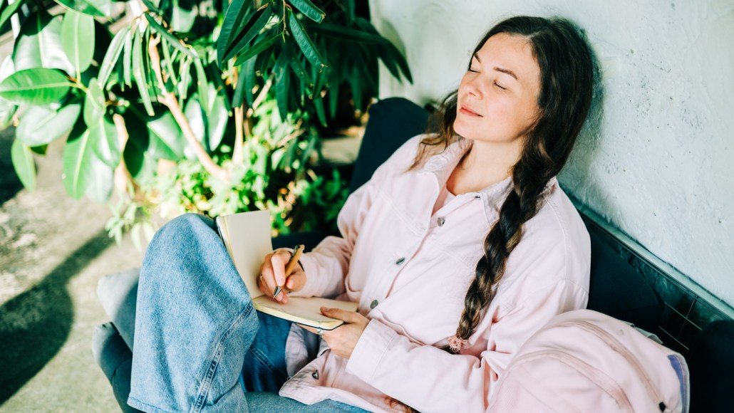 A woman closes her eyes and leans back on a couch
