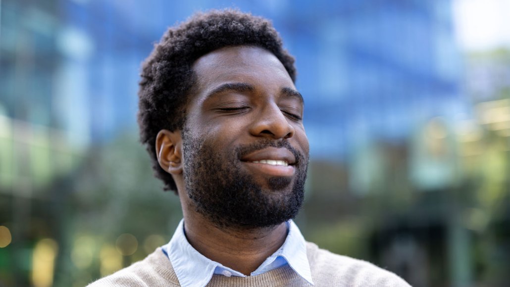 A man stands outdoors with his eyes closed, as if focusing on a mental image.