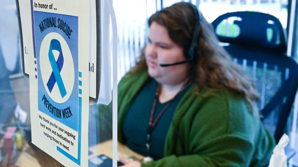 An intervention specialist sits at a desk with at a crisis center, taking a call from the 988 lifeline