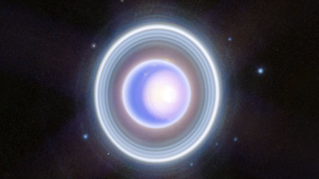 Uranus appears as a pale blue disk encircled by several faint, bright rings.