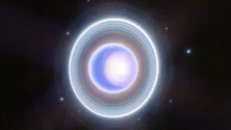 Uranus appears as a pale blue disk encircled by several faint, bright rings.