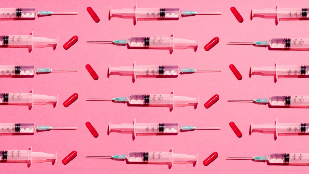 Partially filled syringes and red pill capsules are laid in a pattern on a pink background, in a way to illustrate how peptides may be administered.