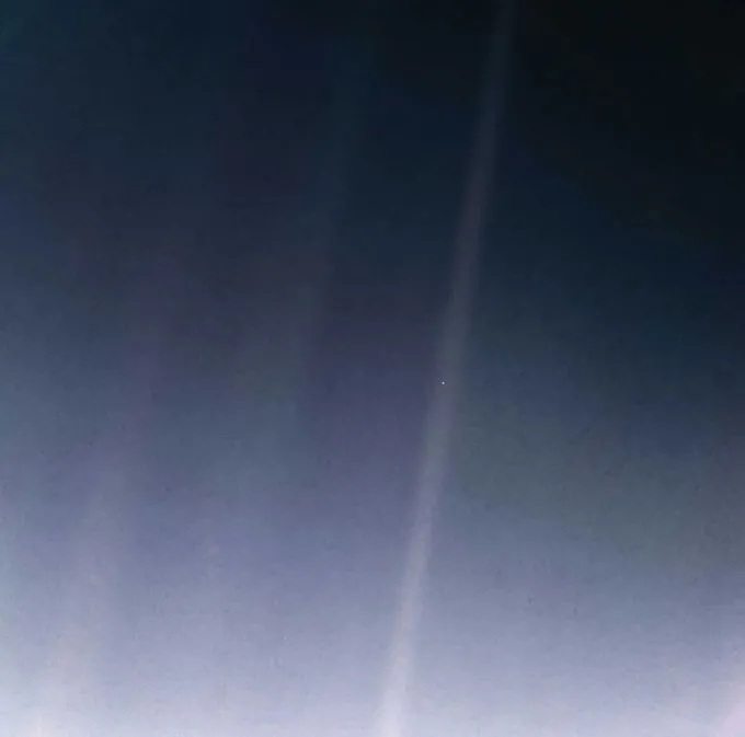 A faint beam of light crosses a dark sky, with a tiny bright dot near its center.