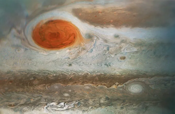 Jupiter’s Great Red Spot appears as a large reddish storm amid swirling cloud bands.