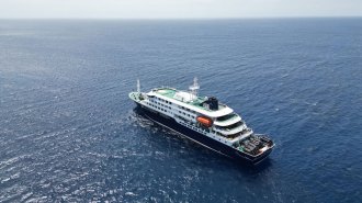 A small cruise ship is shown from an aerial view in open water. This ship has had an outbreak of hantavirus.
