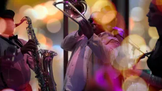 A trio plays musical instruments, including a saxophone and a trombone.