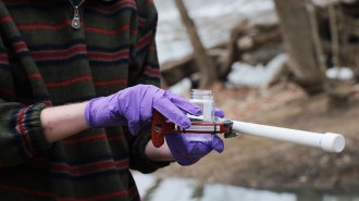 Closeup photo of a water sample kit held by a Potomac River Keeper Network employee wearing disposable latex gloves