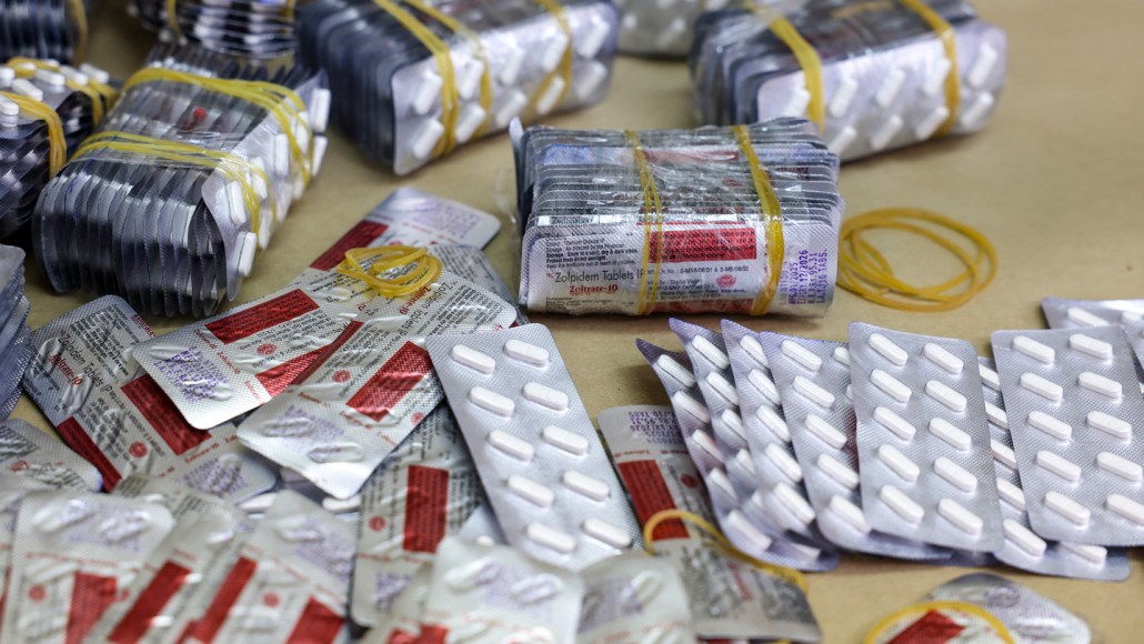 Dozens of foil blister packs of white oval and round tablets, several bundled with yellow rubber bands.
