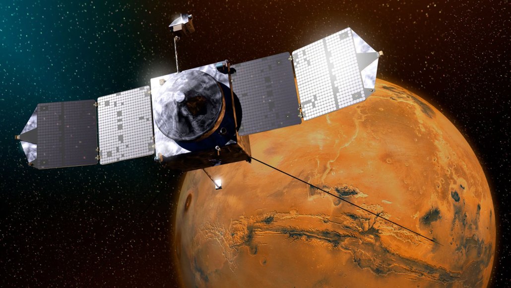 NASA's MAVEN orbiter crosses in front of Mars, its twin solar panels spread wide against a star field.