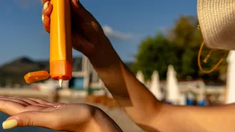 Close-up view of someone squeezing sunscreen into their hand.