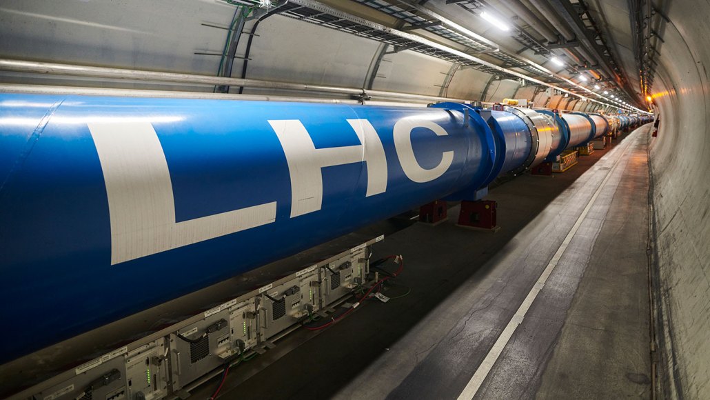 Scientific equipment with "LHC" written on it is pictured in a long tunnel.
