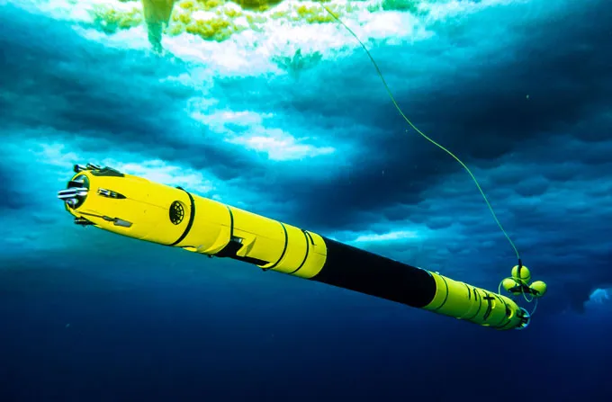 A long narrow tube that's yellow at the ends, black in the middle, floats in the water under ice. It will be used to probe ice melt in Greenland.
