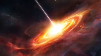 A quasar illustrated as a bright white, yellow and orange disk of swirling material on a black background.