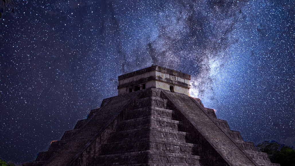 A stepped stone pyramid rises against a night sky filled with stars.