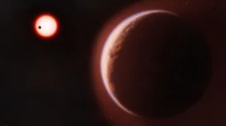 illustration: front-right is a mostly dark exoplanet with a red hue and back left is a smaller white-ish planet with a glowing red hue and a smaller black dot appearing in the white hue