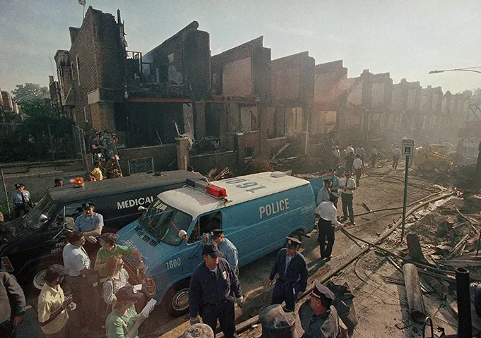 An emergency vehicle parked in front of buildings that show evidence of destruction.