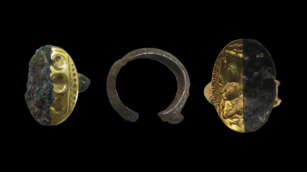 Three ancient rings are seen on a black background. The one in the middle is just the part that goes around the finger, while the other two have flat engraved ovals. Each have a half showing what the rings would have looked like originally.