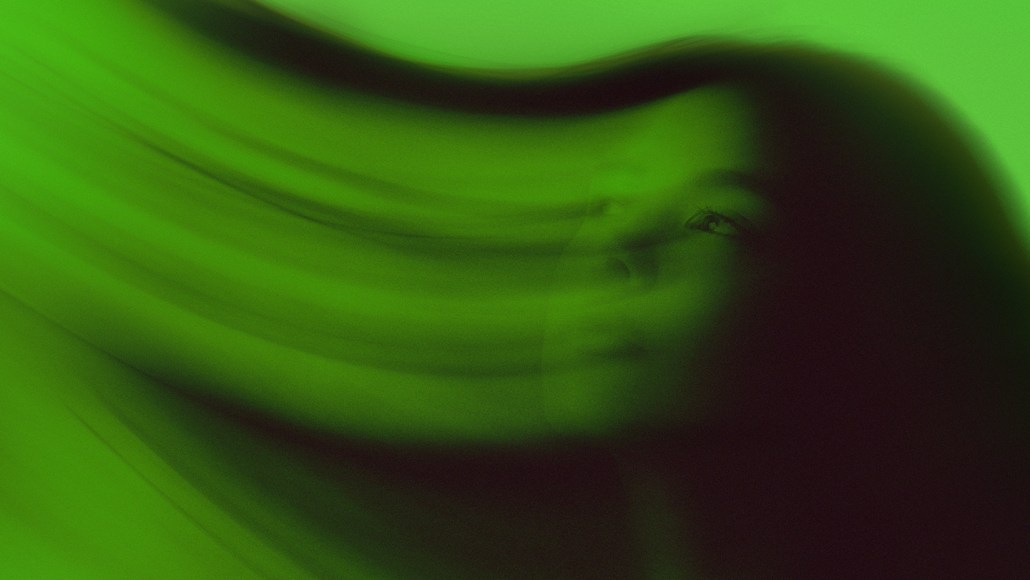 A swirly, artistic green image of a woman's head.